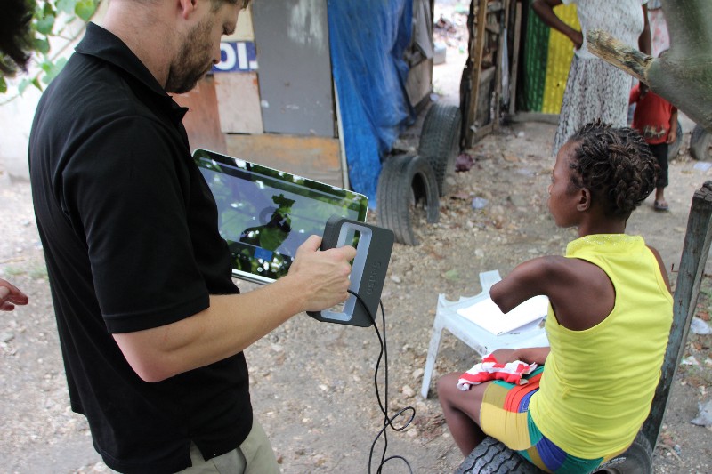 Danis' limb being scanned by Jeff Erenstone near her home in the Airport tent city. Photo via Enable Community Foundation.